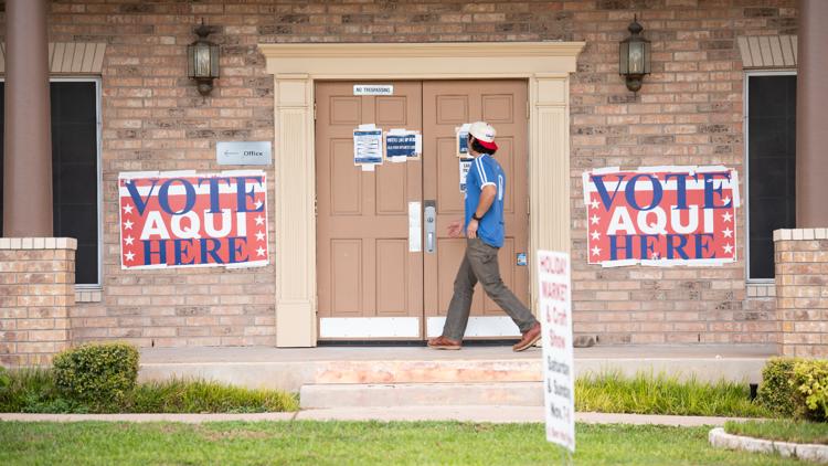 Early voting sign outside a polling location in Austin, Texas, with diverse people entering to cast ballots.